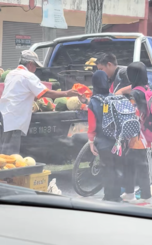 An uncle who sells fruits was giving free watermelon slices to children after school