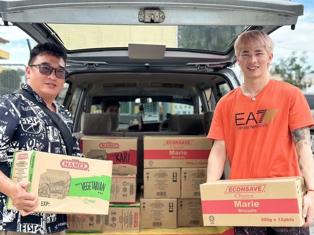 Chen Tang Jie and a PKSU representative delivering boxes of essential food supplies to support underprivileged communities