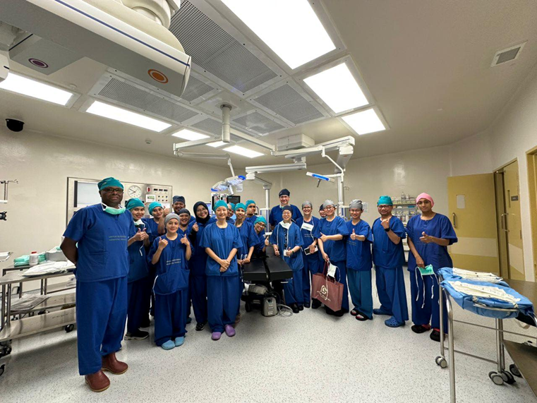 A team of medical professionals in blue scrubs gathered in an operating room, dedicated to spina bifida care