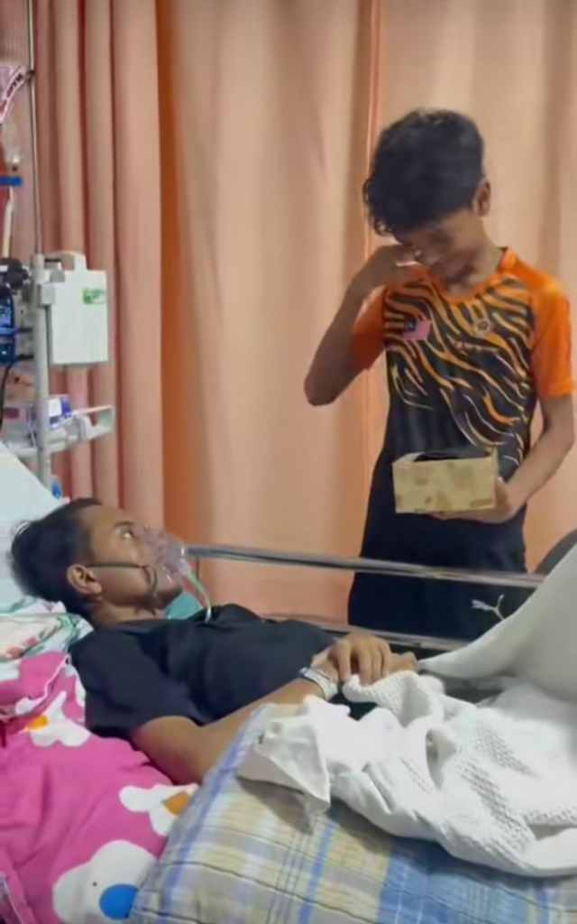 Screenshot from the video shows Aidil beside his brother as he pulls out a box from under his blanket.