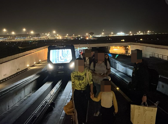 Individuals were pulling the luggage and navigating the dimly lit track under airport personnel's guidance as the aerotrain was disrupted
