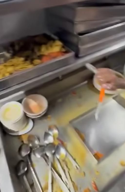 The employee was seen cleaning up the trays of leftover food, separating the meat and vegetables. 